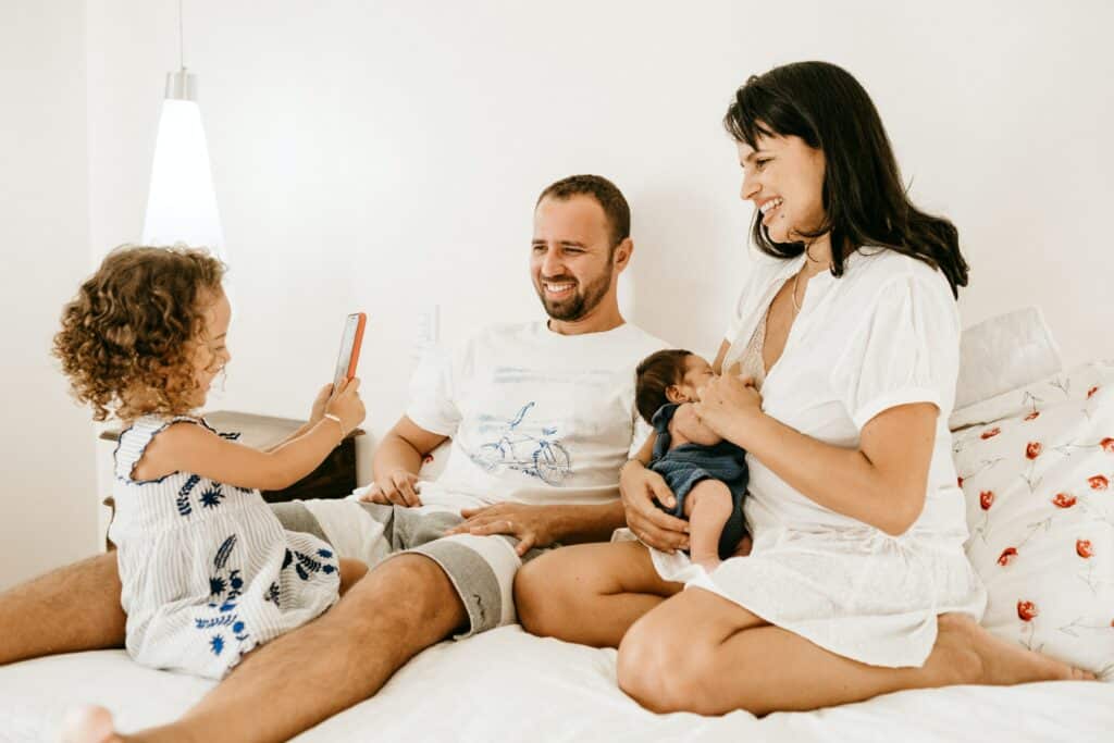 A young family laughing in bed, the mother is breast feeding