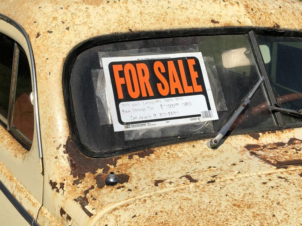 A for sale sign on a rusted car